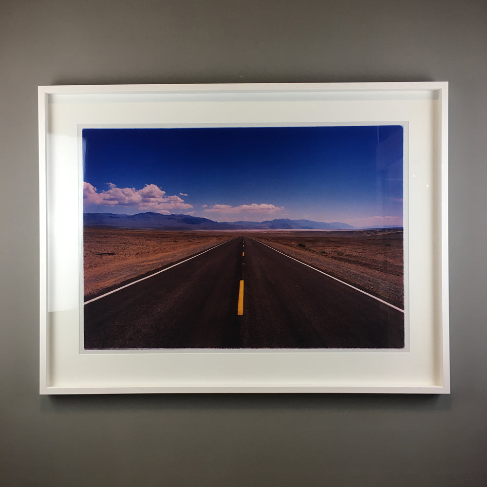 A photograph of Death Valley in the Nevada desert, with a long, winding road stretching into the distance