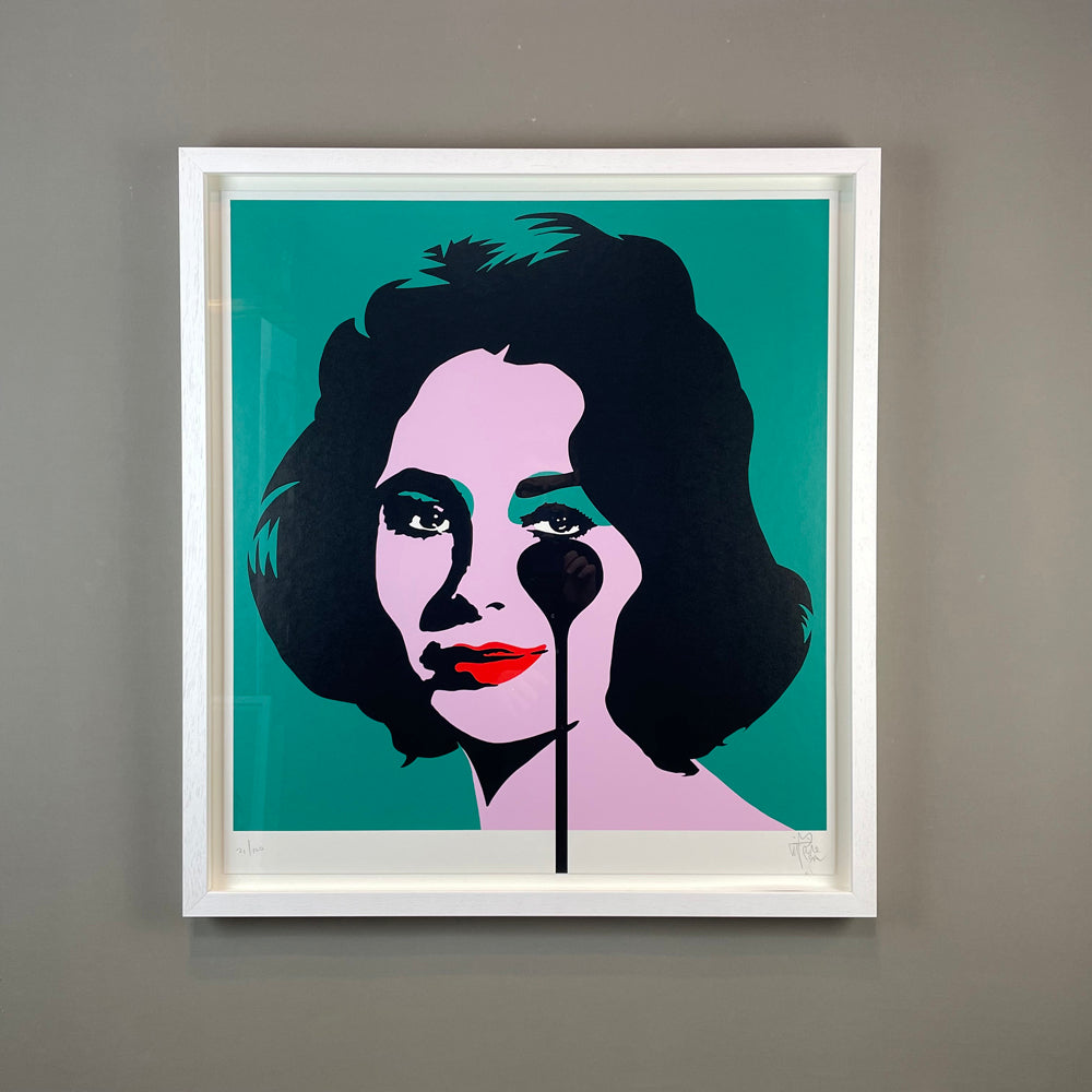 A portrait of Liz Taylor in a contemporary style, featuring black paint dripping from her eye onto a turquoise background. The image showcases an artistic representation of Liz Taylor in a white frame